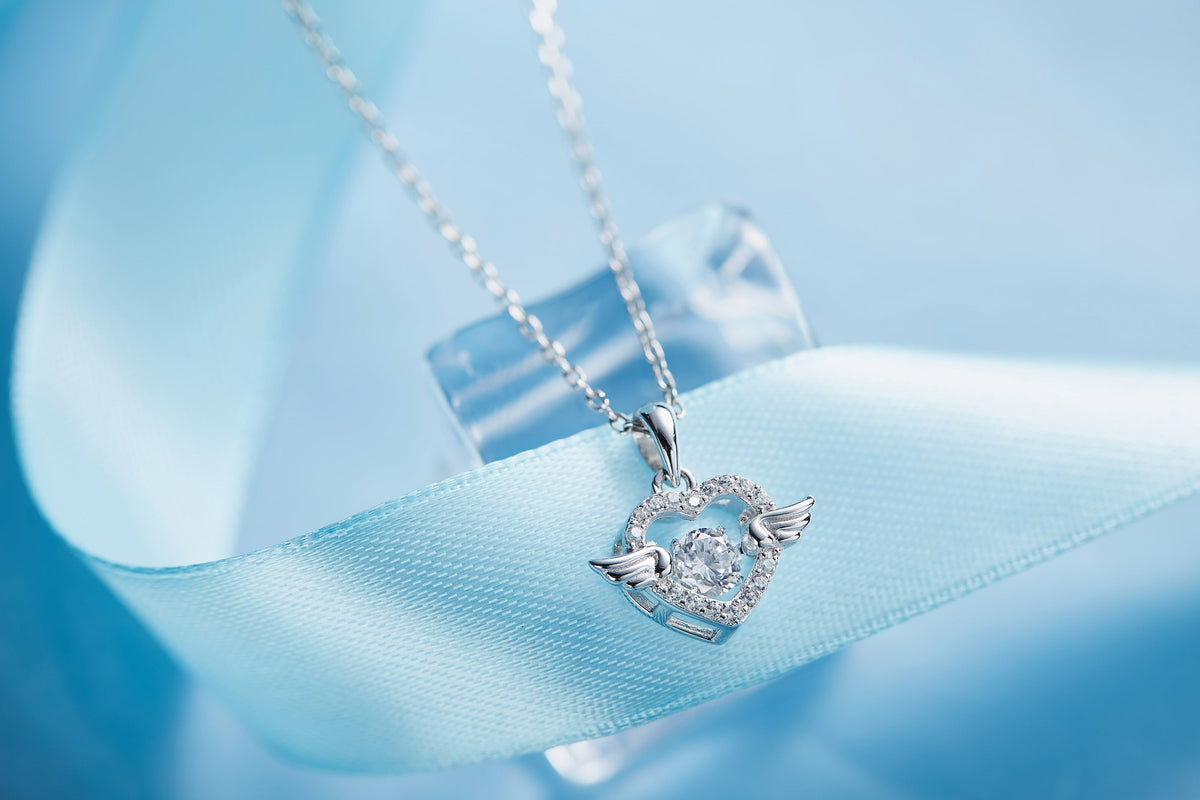 Sterling silver angel wing necklace with heart-shaped pendant and sparkling accents on a delicate chain