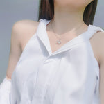 Sterling silver angel wing necklace featured on a model wearing a white blouse in natural light