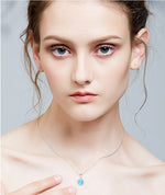 Elegant model showcasing a sterling silver opal necklace with a shimmering blue opal pendant